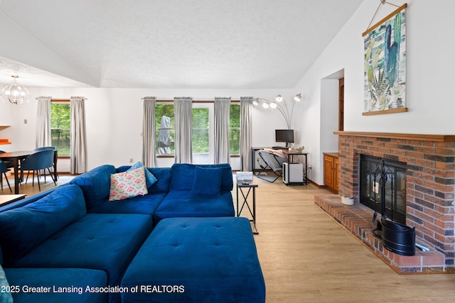 2440 Sower Blvd, Okemos, MI 48864 - living area with vaulted ceiling, a brick fireplace, wood finished floors, a chandelier, and a textured ceiling