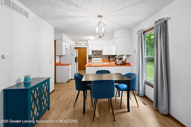 2440 Sower Blvd, Okemos, MI 48864 - dining room with a chandelier, a textured ceiling, and light wood-type flooring