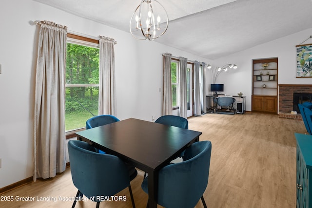 2440 Sower Blvd, Okemos, MI 48864 - dining area featuring a chandelier, light wood finished floors, lofted ceiling, built in features, and a brick fireplace