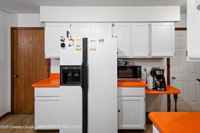 2440 Sower Blvd, Okemos, MI 48864 - kitchen with white fridge with ice dispenser, wood finished floors, white cabinets, light countertops, and a textured ceiling
