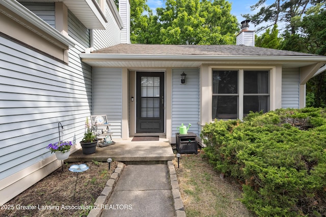 2440 Sower Blvd, Okemos, MI 48864 - doorway to property with a chimney, covered porch, and roof with shingles