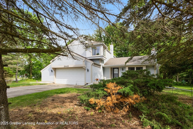 2440 Sower Blvd, Okemos, MI 48864 - traditional home with driveway, a chimney, and an attached garage