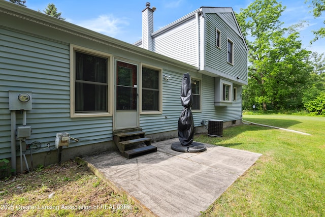2440 Sower Blvd, Okemos, MI 48864 - rear view of property featuring entry steps, a chimney, a lawn, and a patio area