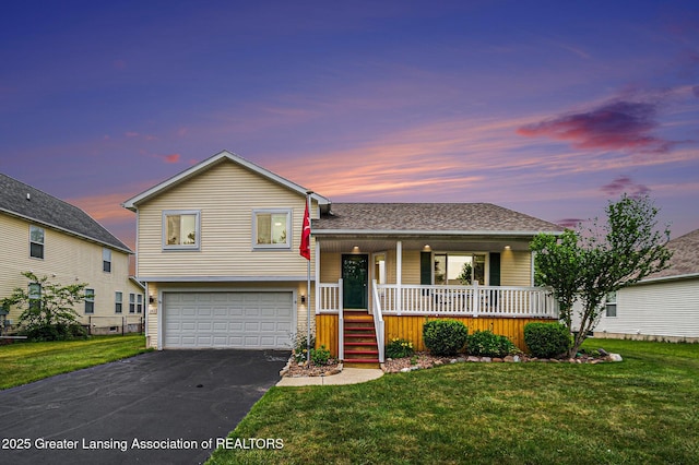 242 Coventry Ln, Mason, MI 48854 - tri-level home featuring a porch, a garage, asphalt driveway, and a front yard