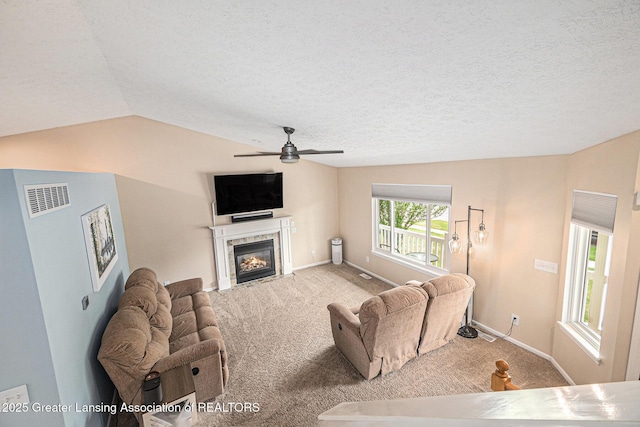 242 Coventry Ln, Mason, MI 48854 - carpeted living area featuring lofted ceiling, ceiling fan, a tile fireplace, and a textured ceiling