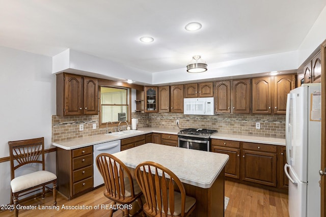 2352 Kings Cross N, East Lansing, MI 48823 - kitchen with white appliances, light countertops, a breakfast bar, and light wood-style floors