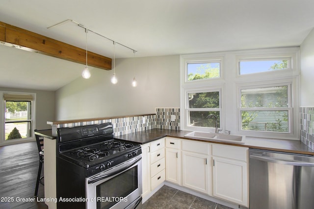 1321 Weber Dr, Lansing, MI 48912 - kitchen featuring dishwasher, gas stove, track lighting, dark countertops, and white cabinetry