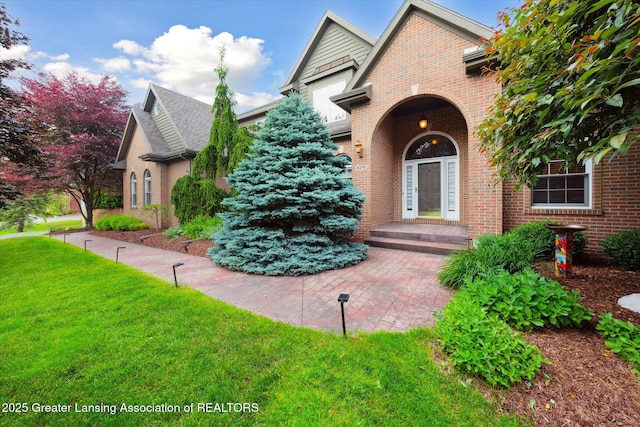 6378 E Island Lake Dr, East Lansing, MI 48823 - view of exterior entry with brick siding and a lawn