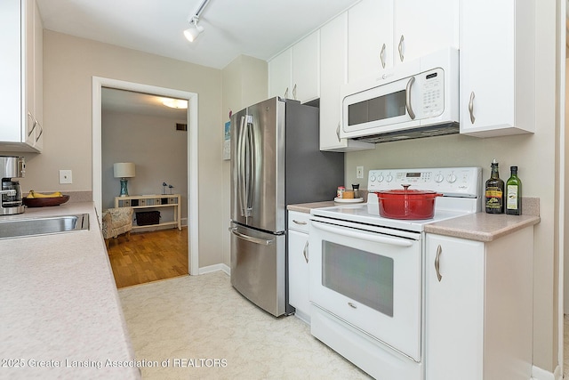 619 Wayland Ave, East Lansing, MI 48823 - kitchen with white appliances, light countertops, white cabinetry, light colored carpet, and rail lighting