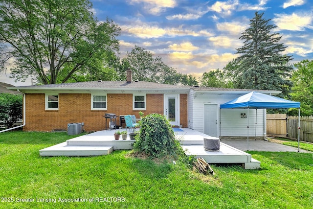 619 Wayland Ave, East Lansing, MI 48823 - back of house at dusk featuring a deck, a chimney, brick siding, and a patio