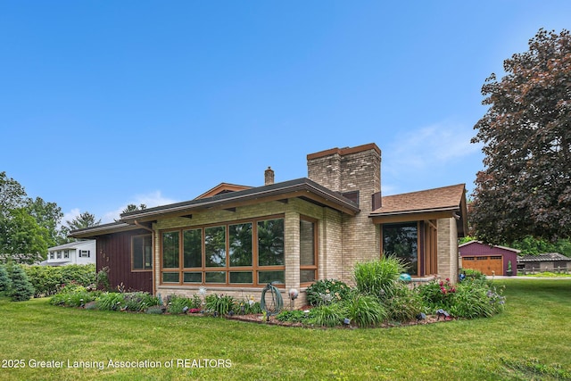 203 Branson Bay Dr, Mason, MI 48854 - rear view of house with a chimney, a lawn, and brick siding