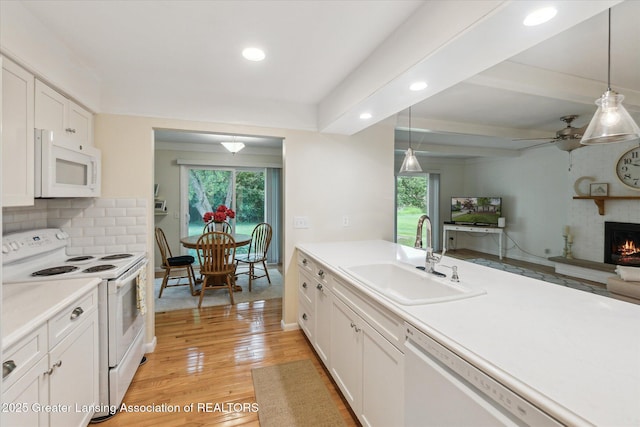 2130 Belding Ct, Okemos, MI 48864 - kitchen featuring white appliances, recessed lighting, light countertops, white cabinets, and a large fireplace