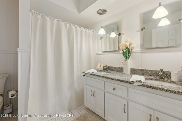 2130 Belding Ct, Okemos, MI 48864 - bathroom with wainscoting, double vanity, tile patterned floors, and a shower with shower curtain