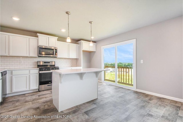 2905 Moccasin Dr, Dewitt, MI 48820 - kitchen with stainless steel appliances, light wood-type flooring, decorative backsplash, a kitchen island, and light countertops