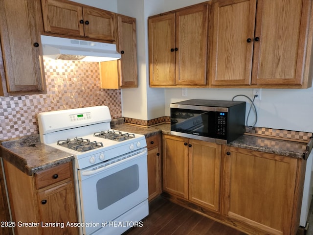 1201 Climax St, Lansing, MI 48912 - kitchen with white gas range oven, stainless steel microwave, under cabinet range hood, dark wood-type flooring, and decorative backsplash