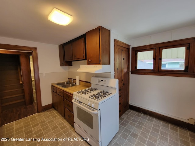1201 Climax St, Lansing, MI 48912 - kitchen featuring white gas range, under cabinet range hood, light tile patterned floors, and light countertops