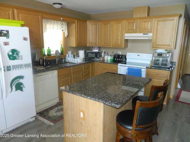 202 Broadway Rd, Houghton Lake, MI 48629 - kitchen featuring under cabinet range hood, white appliances, wood finished floors, a center island, and a kitchen breakfast bar