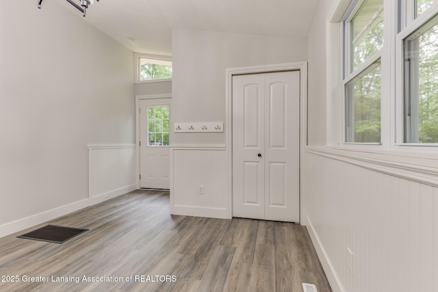 9481 S Clinton Trl, Eaton Rapids, MI 48827 - unfurnished room featuring vaulted ceiling, wainscoting, and light wood finished floors