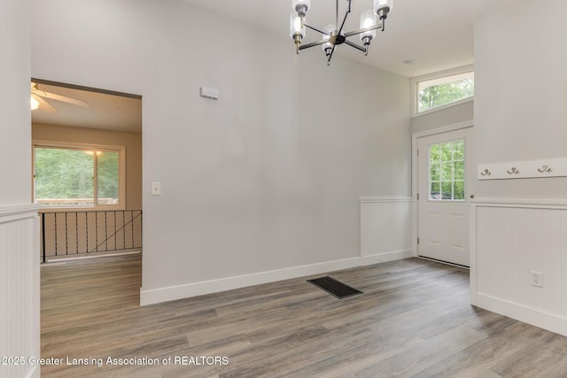 9481 S Clinton Trl, Eaton Rapids, MI 48827 - unfurnished dining area featuring a wainscoted wall, a chandelier, wood finished floors, a ceiling fan, and a high ceiling