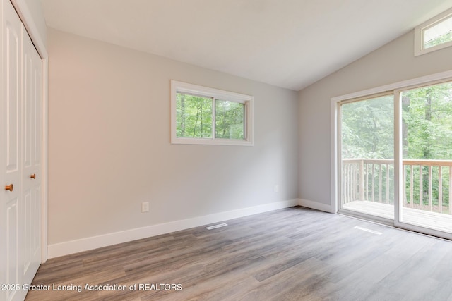 9481 S Clinton Trl, Eaton Rapids, MI 48827 - unfurnished bedroom featuring access to outside, lofted ceiling, wood finished floors, and a closet