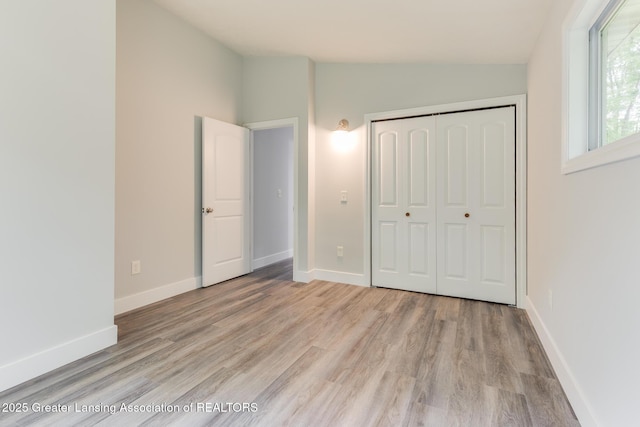 9481 S Clinton Trl, Eaton Rapids, MI 48827 - unfurnished bedroom featuring vaulted ceiling, light wood-style floors, and a closet