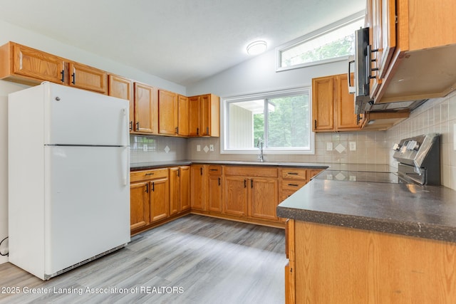 9481 S Clinton Trl, Eaton Rapids, MI 48827 - kitchen with freestanding refrigerator, dark countertops, vaulted ceiling, electric range oven, and backsplash