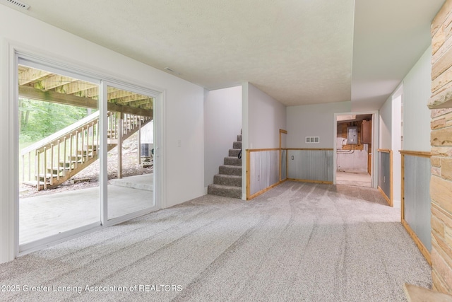 9481 S Clinton Trl, Eaton Rapids, MI 48827 - unfurnished living room with carpet floors, stairway, a textured ceiling, and wooden walls