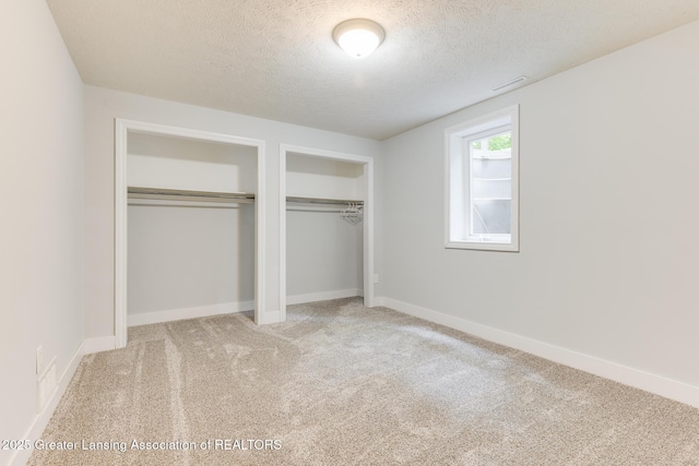 9481 S Clinton Trl, Eaton Rapids, MI 48827 - unfurnished bedroom with multiple closets, a textured ceiling, and carpet flooring