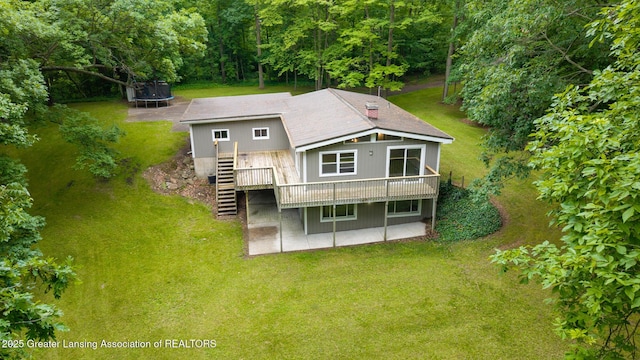 9481 S Clinton Trl, Eaton Rapids, MI 48827 - rear view of house with a trampoline, stairway, a yard, a wooden deck, and a patio area