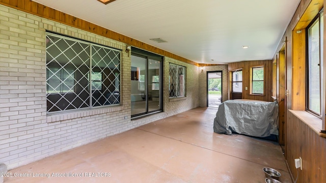 62 W Sherwood Rd, Okemos, MI 48864 - sunroom with finished concrete flooring, brick wall, and wooden walls