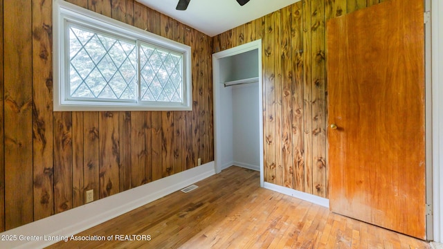 62 W Sherwood Rd, Okemos, MI 48864 - unfurnished bedroom with wood finished floors, a closet, wooden walls, and a ceiling fan
