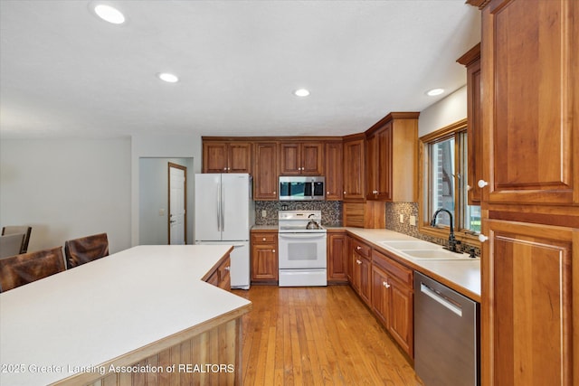 4084 Hulett Rd, Okemos, MI 48864 - kitchen with appliances with stainless steel finishes, backsplash, light countertops, brown cabinetry, and light wood-type flooring