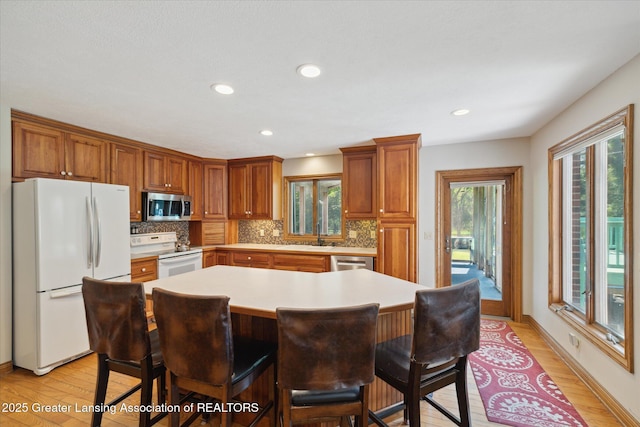 4084 Hulett Rd, Okemos, MI 48864 - kitchen with appliances with stainless steel finishes, light wood-style floors, light countertops, decorative backsplash, and recessed lighting