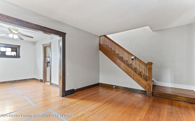 1017 W Oakland Ave, Lansing, MI 48915 - unfurnished living room featuring wood finished floors, stairs, and ceiling fan