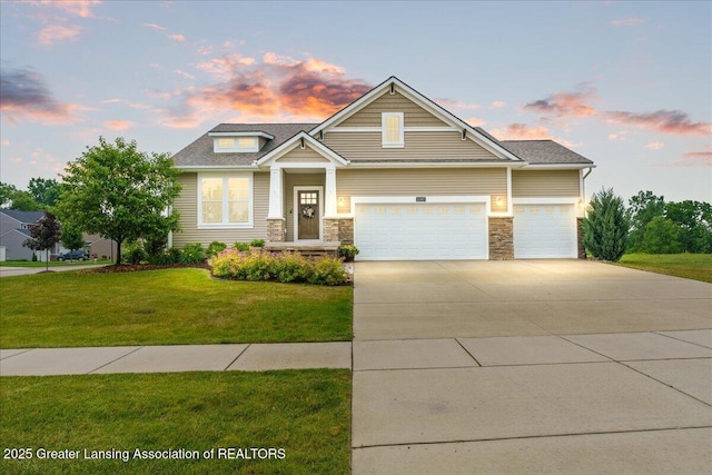 11167 Windswept Dr, Grand Ledge, MI 48837 - view of front facade with a yard, concrete driveway, a garage, and stone siding