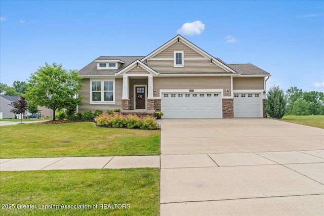 11167 Windswept Dr, Grand Ledge, MI 48837 - craftsman house featuring an attached garage, a front yard, driveway, and stone siding