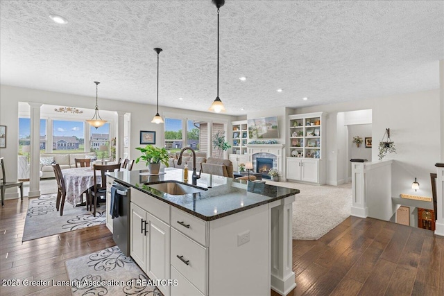 11167 Windswept Dr, Grand Ledge, MI 48837 - kitchen featuring dark wood-style floors, open floor plan, a kitchen island with sink, dark stone countertops, and a textured ceiling