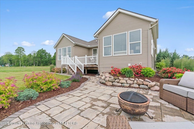 11167 Windswept Dr, Grand Ledge, MI 48837 - back of property with a fire pit, a patio area, a deck, and a lawn