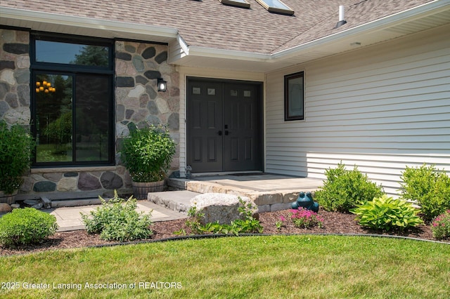 2605 College Rd, Holt, MI 48842 - doorway to property featuring roof with shingles, stone siding, and a yard