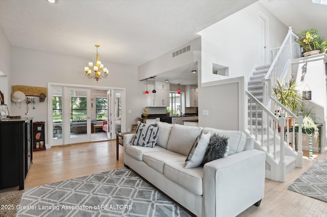 2605 College Rd, Holt, MI 48842 - living room featuring light wood-type flooring, stairway, and a chandelier