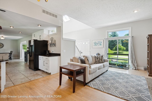 2605 College Rd, Holt, MI 48842 - living room featuring plenty of natural light, light wood-style flooring, stairway, and a textured ceiling