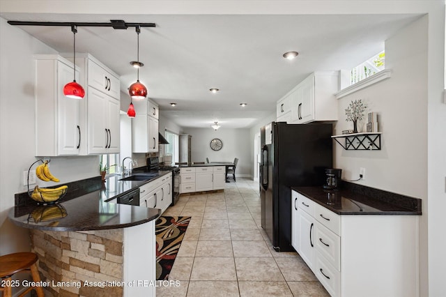 2605 College Rd, Holt, MI 48842 - kitchen featuring gas range, a peninsula, dark countertops, black refrigerator with ice dispenser, and healthy amount of natural light