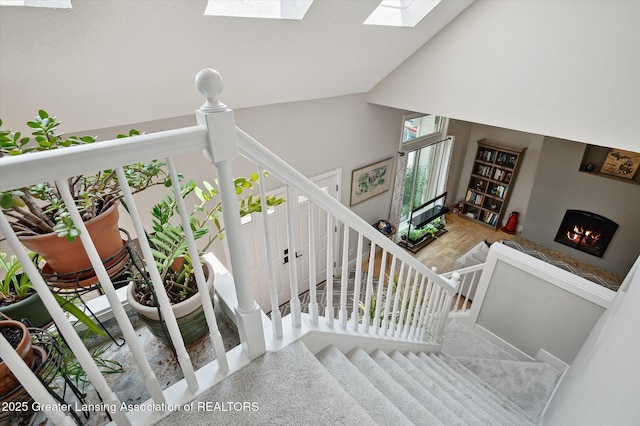 2605 College Rd, Holt, MI 48842 - staircase with a skylight, a warm lit fireplace, and vaulted ceiling