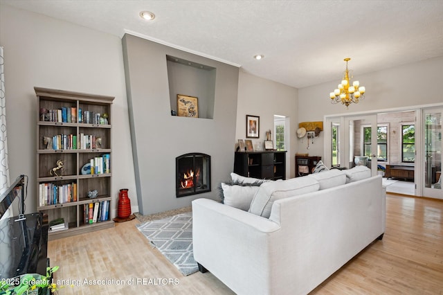 2605 College Rd, Holt, MI 48842 - living area featuring a warm lit fireplace, wood finished floors, a chandelier, and recessed lighting