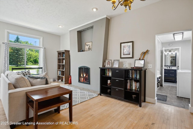 2605 College Rd, Holt, MI 48842 - living room with a warm lit fireplace, hardwood / wood-style floors, recessed lighting, a chandelier, and a textured ceiling