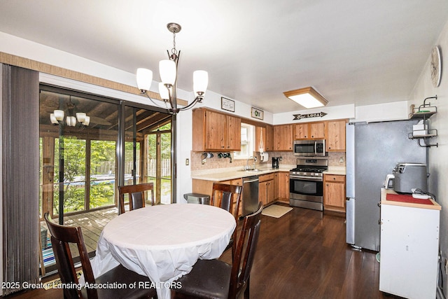 1614 N Eifert Rd, Holt, MI 48842 - kitchen featuring appliances with stainless steel finishes, a chandelier, dark wood-style floors, light countertops, and tasteful backsplash