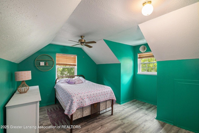 1614 N Eifert Rd, Holt, MI 48842 - bedroom featuring wood finished floors, a textured ceiling, vaulted ceiling, multiple windows, and ceiling fan