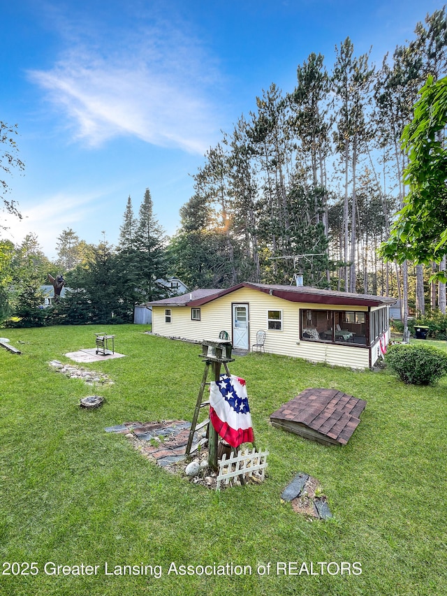 103 Norway Rd, Roscommon, MI 48653 - rear view of property featuring a fire pit, a lawn, and a sunroom
