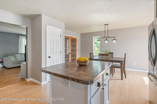774 Tims View St, Potterville, MI 48876 - kitchen featuring dark countertops, light wood-style flooring, smart refrigerator, white cabinetry, and pendant lighting