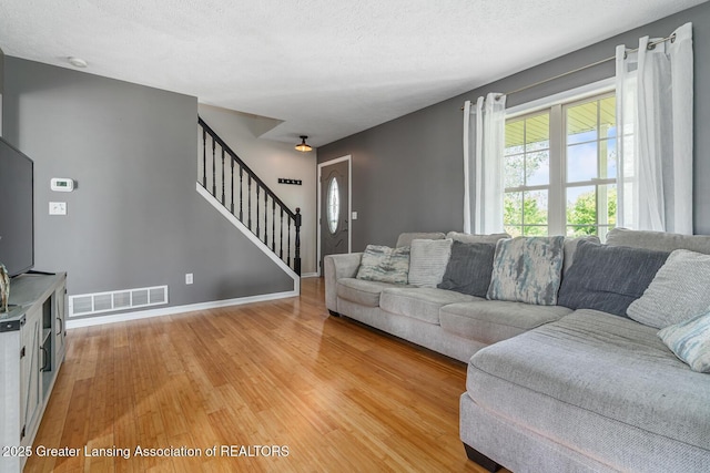 774 Tims View St, Potterville, MI 48876 - living room with light wood-style flooring, stairs, and a textured ceiling